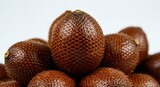 Pile of ripe salak fruit with textured skin on white background