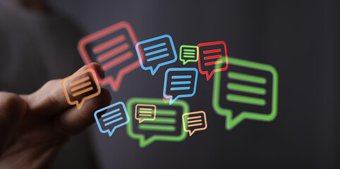 Concept showing digital communication using speech bubbles with a man's hand reaching to touch the icons and represent modern connection.