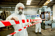 © BESTIMAGE - Man inspector scientist investigate chemical gas leak spill with safety face mask PPE suit in area closed barricade security red white tape. danger area infected toxic leak spill cross stripe ribbon