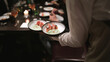 © Sceliano - Waiter bringing out two bowls of a crudo dish on one hand during busy seafood night at the restaurant.