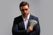 © Volodymyr - Business man in t-shirt with cash money dollars banknotes isolated on yellow studio background. Hundred dollar bill, financial concept.