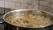 © Nandar - A stainless steel pot of boiling lentil soup with herbs and spices simmering on a stove.