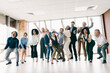 © deagreez - Dynamic group of professionals celebrating teamwork and success in a bright modern office setting