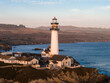 © Aerial Film Studio - Pigeon Point Lighthouse stands on California's rugged coast, with its red topped lantern room, historic buildings, and cliffs lit by a golden sunset.