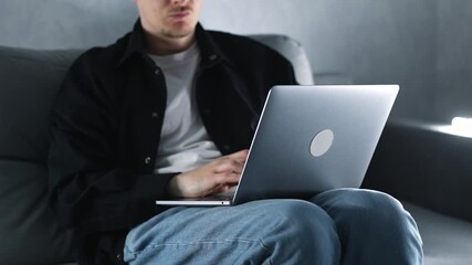 A programmer or system administrator working on a computer at home on the couch.
Online work and typing on a laptop.
A freelancer in a black shirt on the couch at home.