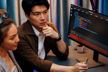IT developers discussing with point to intelligent website development coder system running data online two screens information technology at neon light room at modern office. Infobahn.