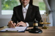 © Natthawadee - Female lawyer reviewing legal documents at office desk with gavel, justice scale, and contract papers, symbolizing law, judgment, and legal consulting.