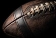 © Sada - Close-up of a worn, leather American football against a stark black background