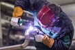 © exotic - Close-up of a welder working on a metal pipe with protective gear in a workshop