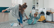 © ABCreative - A cheerful son plays in the laundry room, sitting inside a bowl of clothes. His mother gently pulls him, enjoying their playful moment during chores.