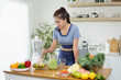 © matinee - Young woman preparing a fresh vegetable salad in modern kitchen. Concept of clean eating and healthy lifestyle.