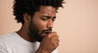 © Irina - Black man coughing while covering his mouth in a neutral setting