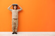 © New Africa - Cute boy measuring his height near orange wall indoors. Space for text