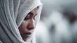 © faldsaj - Contemplative woman wearing a traditional white headscarf in soft light