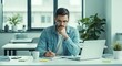 © Glyph Studio - Young man working from home office thoughtfully writing and using laptop