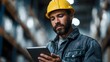 © Bussakon - A male warehouse worker wearing a yellow hard hat examines a tablet overseeing inventory and logistics in an industrial setting