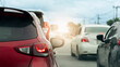 © thongchainak - Rear side of red car with turn on brake light. Traffic jam on the road. Many cars stopped to cross the intersection. Blurred background of electric pole and trees and other car driving on the road.