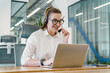 © muse studio - Young woman engaged in online communication at modern office workspace