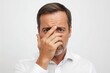 © The 2R Artificiality - Man with short hair and beard covering his face with his hand showing a facial expression of embarrassment on a plain white background