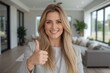 © The 2R Artificiality - Smiling woman with long blonde hair gives thumbs up gesture in modern living room with large windows and contemporary furniture.