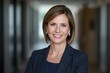 © The 2R Artificiality - Professional woman with short hair wearing a business suit smiling in a modern office hallway with soft lighting and blurred backgrounds