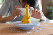 © Sophon_Nawit - A waist-up, shallow depth of field photo of a high school student performing a 3D scan of a bright yellow giraffe figurine using a smartphone and a DIY turntable.