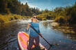 © OlegKovalevich - Sunny day and woman on paddle board with sunshine, water sport and vacation on river for tourism.
