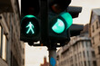 © K - Traffic lights showing green pedestrian walk signal and green car light at city intersection surrounded by European buildings, symbolizing coordinated urban movement and safety system