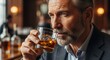 © Vyacheslav - Senior Caucasian man with gray hair and beard holding a whiskey glass in bar setting with warm lighting. Concept of lifestyle, alcohol, leisure, and mature masculinity