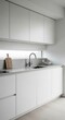 © fatkulmunif - Modern minimalist kitchen with white cabinetry, light grey countertop, sleek black faucet, and a horizontal window providing diffused light, creating a clean and bright contemporary interior.