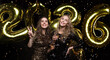 © ty - Two young ladies drinking champagne. Image of girls with balloons isolated on black background, having fun at New Year's 2026 Eve Party.