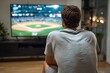 © Netsai - Rear view of a man engrossed in watching a baseball game on a large TV screen in a dimly lit living room, showcasing a relaxed evening at home.