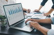© doidam10 - Business data analysis concept with colleagues reviewing financial report on laptop, pointing at chart with growth graph, teamwork discussing statistics, planning strategy and corporate success.