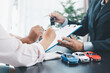 © doidam10 - Customer receiving car key from dealer after signing contract, successful auto purchase and finance agreement at office desk, concept of vehicle loan, leasing, insurance or ownership. vehicle loan.