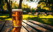© Jae - A cold pint of beer sits on a wooden table outdoors in a sunlit park or beer garden.