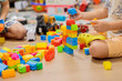 © Татьяна Швец - child playing with blocks.  Close-up of children's hands building tall tower with colorful wooden blocks on floor