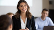 © Kateryna - Confident businesswoman leading a team meeting in a modern office, smiling as she delivers a presentation to colleagues. Professional speaker in a blazer and white blouse engaging the audience during
