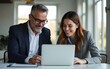 © wu - Business team of two executives working together using laptop in office. Happy young business woman manager showing project presentation to mature man client, investor or partner at work meeting.