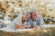 © Daniel - Beautiful cute couple of seniors lying down together hugging and enjoying a tender moment outdoors in green park smiling with happiness. Two pensioners resting close showing love and intimacy.