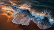 © Alunn cans - Golden hour light illuminates powerful ocean waves breaking on a pristine sandy beach from an aerial view.