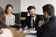 © fizkes - Lively group of young diverse entrepreneurs laugh at workplace desk