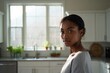© Aliaksandr Barouski - Woman stands in bright kitchen looking toward camera with calm expression