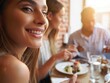 © Aliaksandr Barouski - Woman smiles at a dining table with friends enjoying a meal