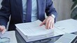 © volha_r - Adult businessman or auditor examining documents with magnifying glass. Professional in a suit scrutinizes financial reports, detail-focused work concept