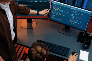 Top view of IT developers discussing with point to intelligent website development coder system running data online two screens information technology at neon light room at modern office. Infobahn.
