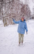 © StockMediaSeller - Elderly woman in a blue winter coat walking through a snowy forest path and pointing toward a snow-covered tree branch. She enjoys the calm beauty of nature on a peaceful winter day.