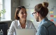 © happy - Happy busy young smiling professional business woman employee, financial advisor or company manager consulting female client, talking to colleague working in office using laptop sitting at desk.