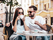 © halayalex - Smiling beautiful woman and her handsome boyfriend. Happy cheerful family. Couple drinking coffee in restaurant. They drinking tea at cafe in street. Holding cup. Enjoying their date. In sunglasses
