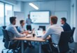 © Andrew - Blurred view of a business team meeting in a modern conference room with a presentation on a screen.
