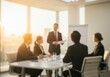 © Andrew - Business leader presenting to colleagues in a sunlit conference room.